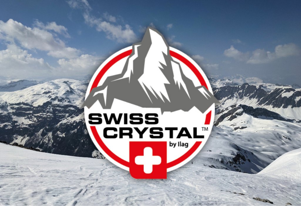 Snowy mountains in the background. In the foreground on white ground a imitation of the Matterhorn in grey. Swiss crystal lettering in black in the middle and the Swiss Cross underneath. The logo is rounded off with a red frame.