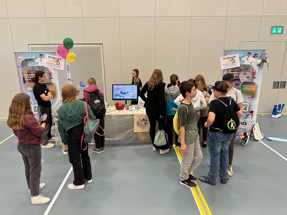 Schülerinen und Schüler vor einem Tisch mit Labor-Ausstellungsstücken