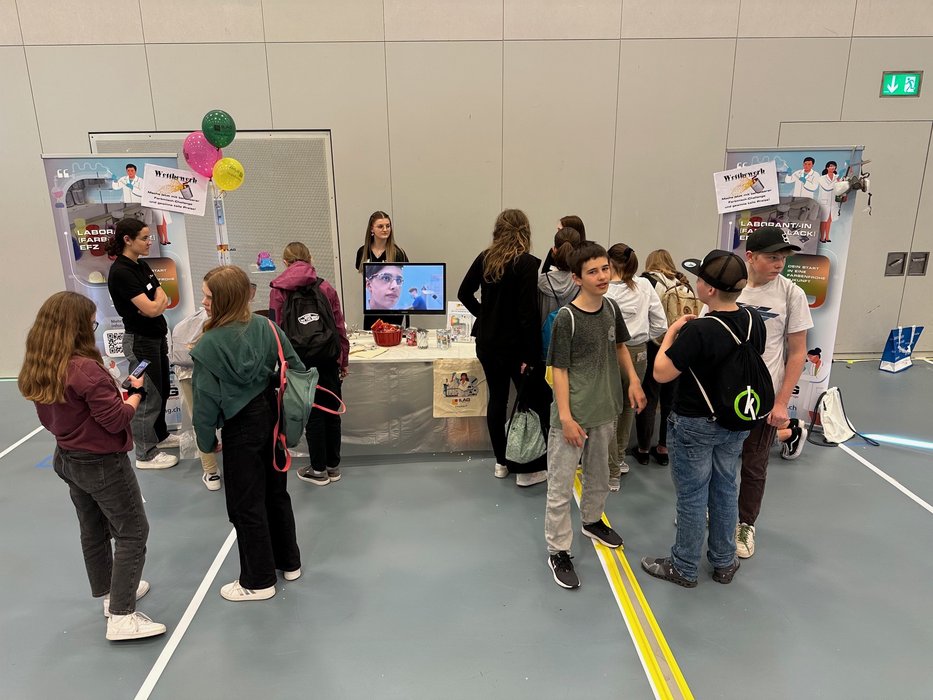 Schülerinnen und Schüler vor einem Tisch mit Labor Ausstellungsteilen