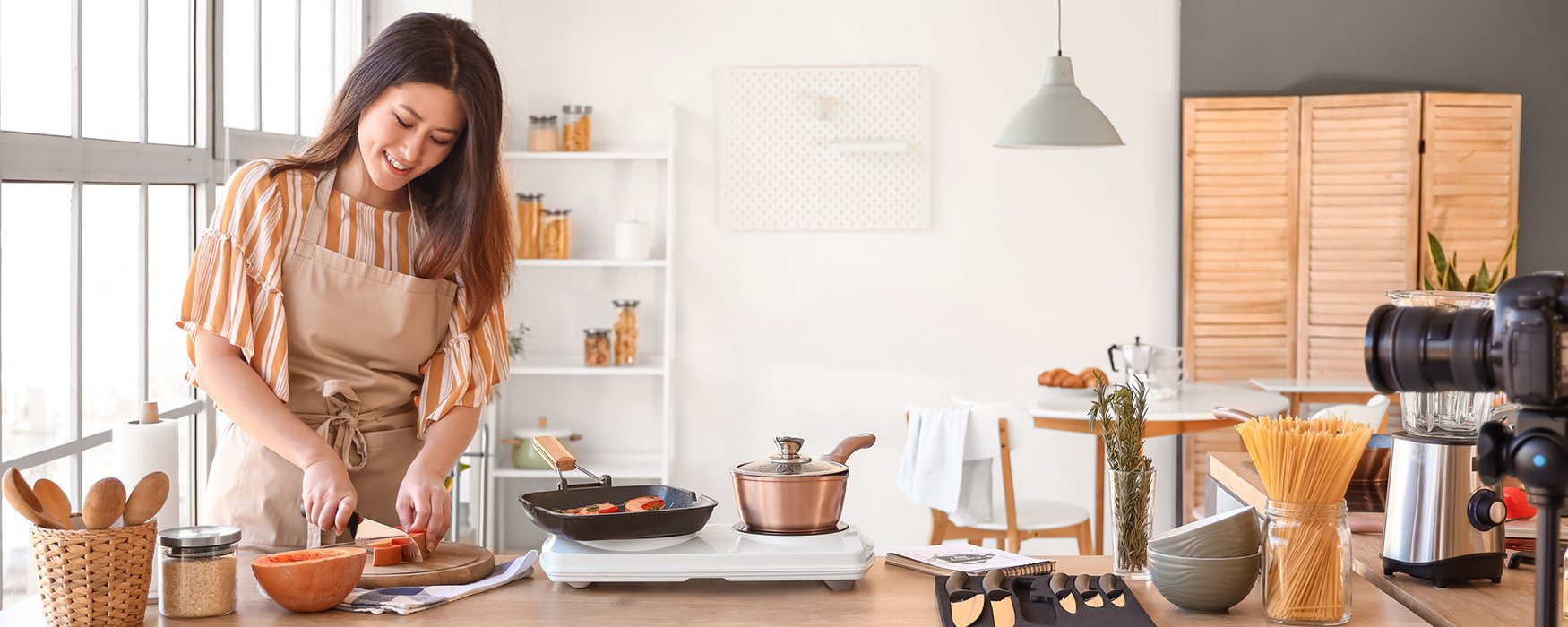 Young woman cuts some pumpkin and places the slices in a square black grill pan on the stove