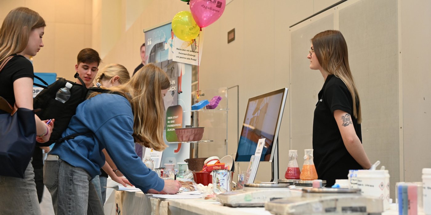 Personen vor dem Tisch mit Labor-Ausstellungsstücken beim Ausfüllen von einem Wetbewerb-Formular