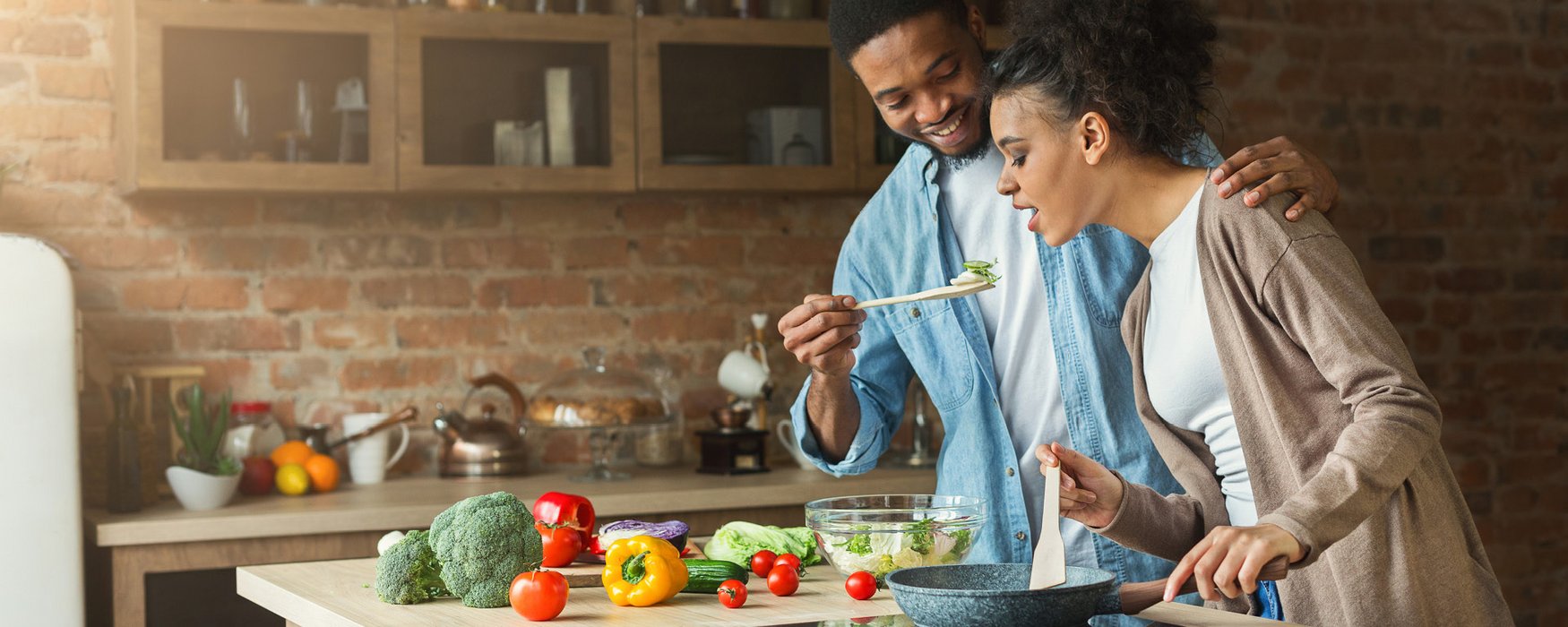 Young couple is cooking and tasting together different vegetables 