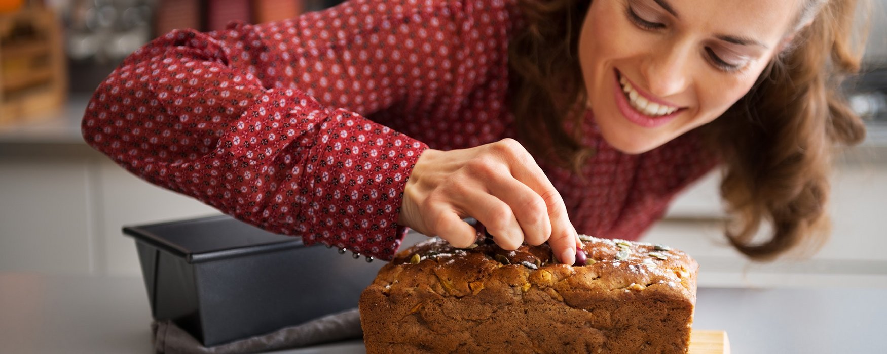 Frau dekoriert einen gebacken Kuchen aus einer Kastenform