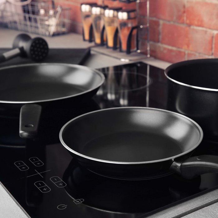 Cooking plate with two black coated frying pans and a black coated pot