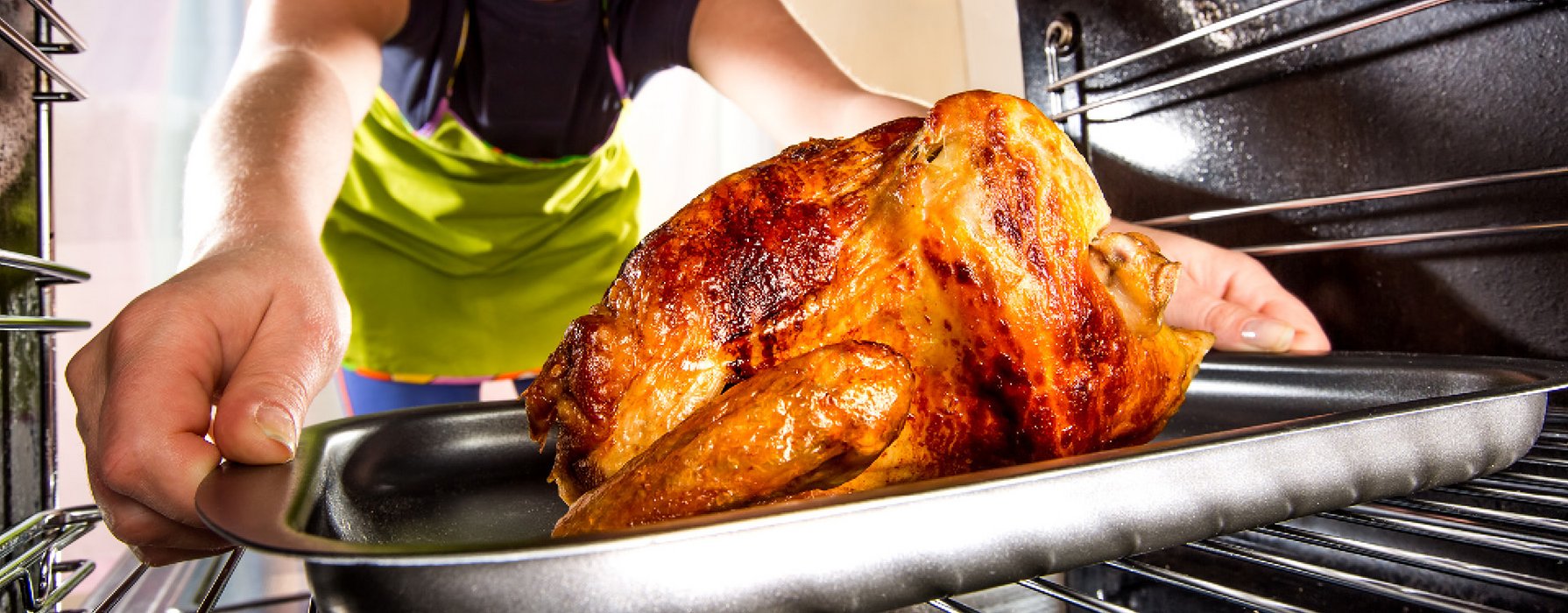 Gegrilltes Huhn wird auf einem Backbleck aus dem Ofen geholt