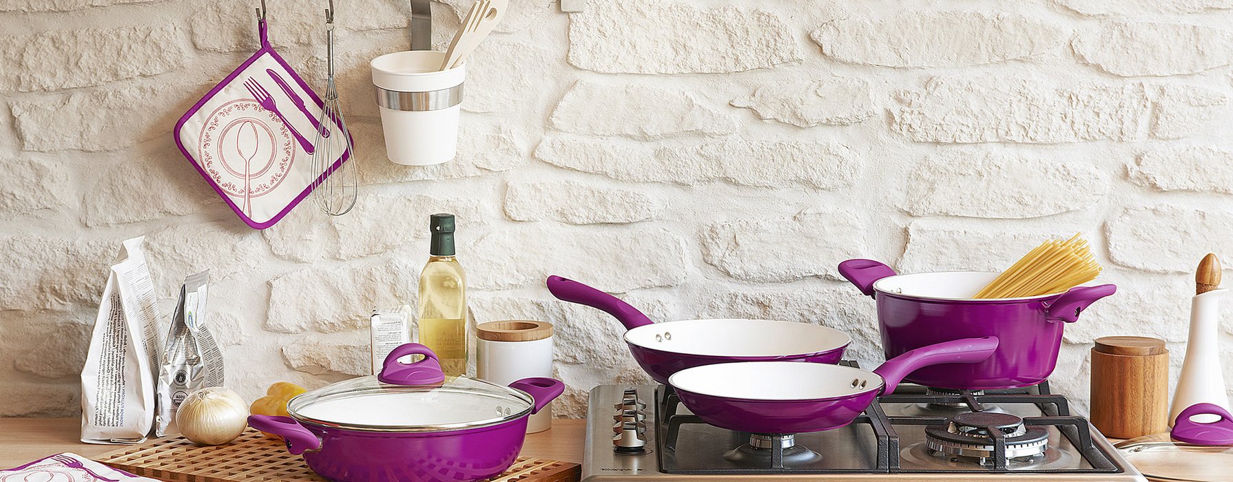 Different pans and pots are draped in a kitchen. They are in different sizes coated in purple on the outside and white on the inside